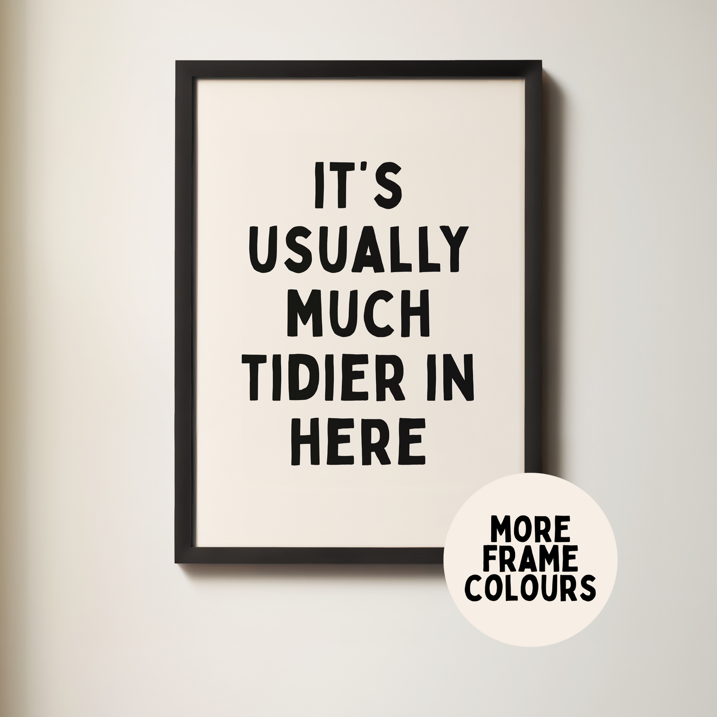 Framed poster with text 'It's usually much tidier in here' on a plain wall.