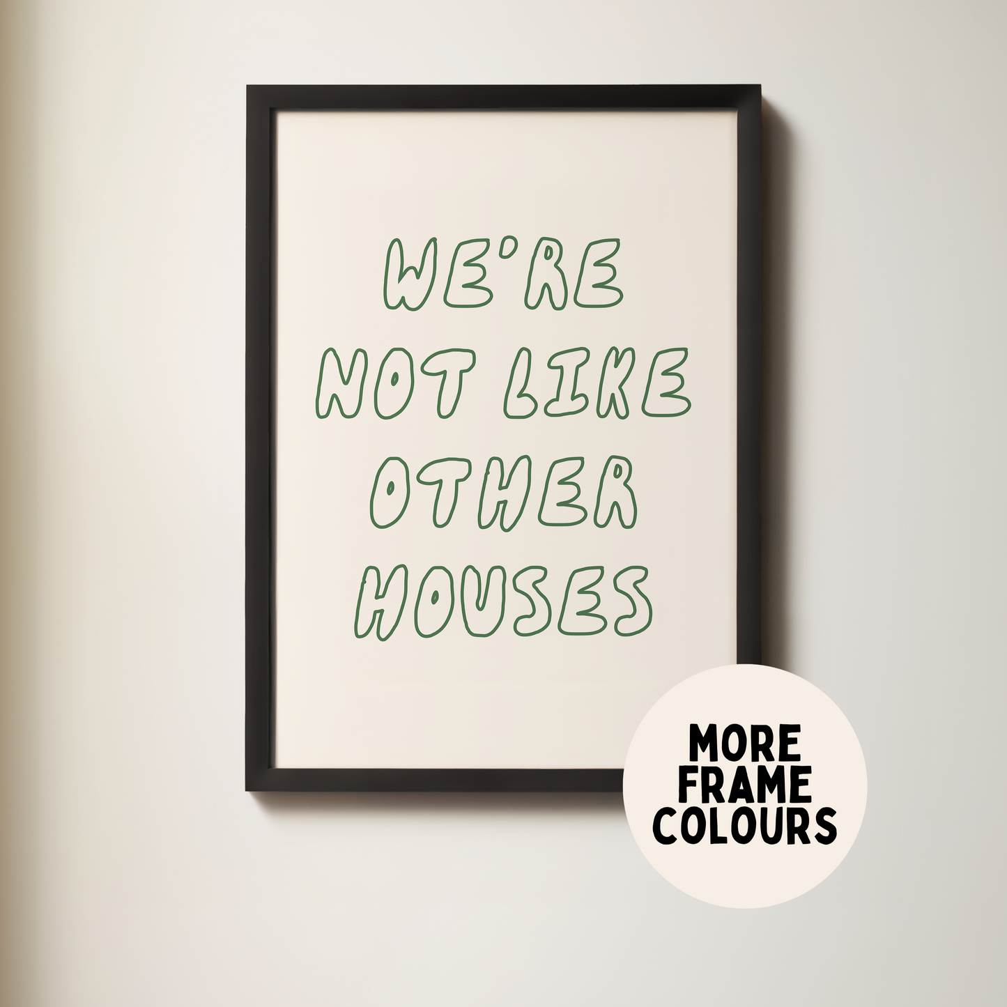 Framed poster with text 'We're not like other houses' on a plain wall.
