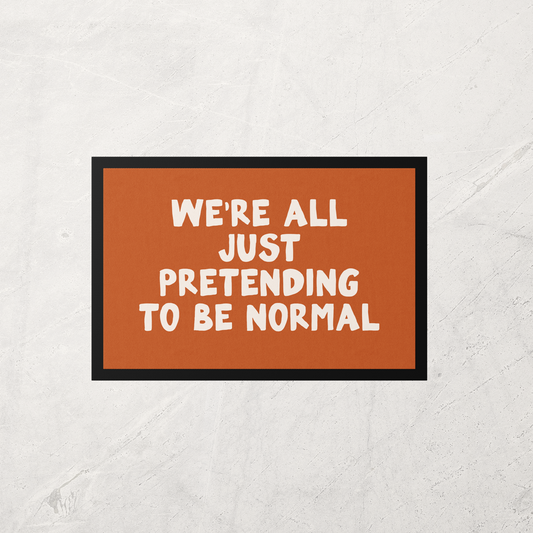 Doormat with text 'WE'RE ALL JUST PRETENDING TO BE NORMAL' on a textured white background
