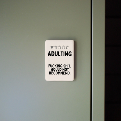 Decorative sign with humorous text on a plain wall