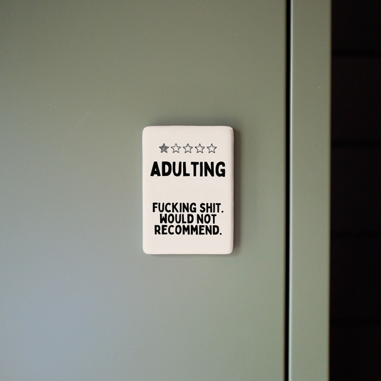 Decorative sign with humorous text on a plain wall