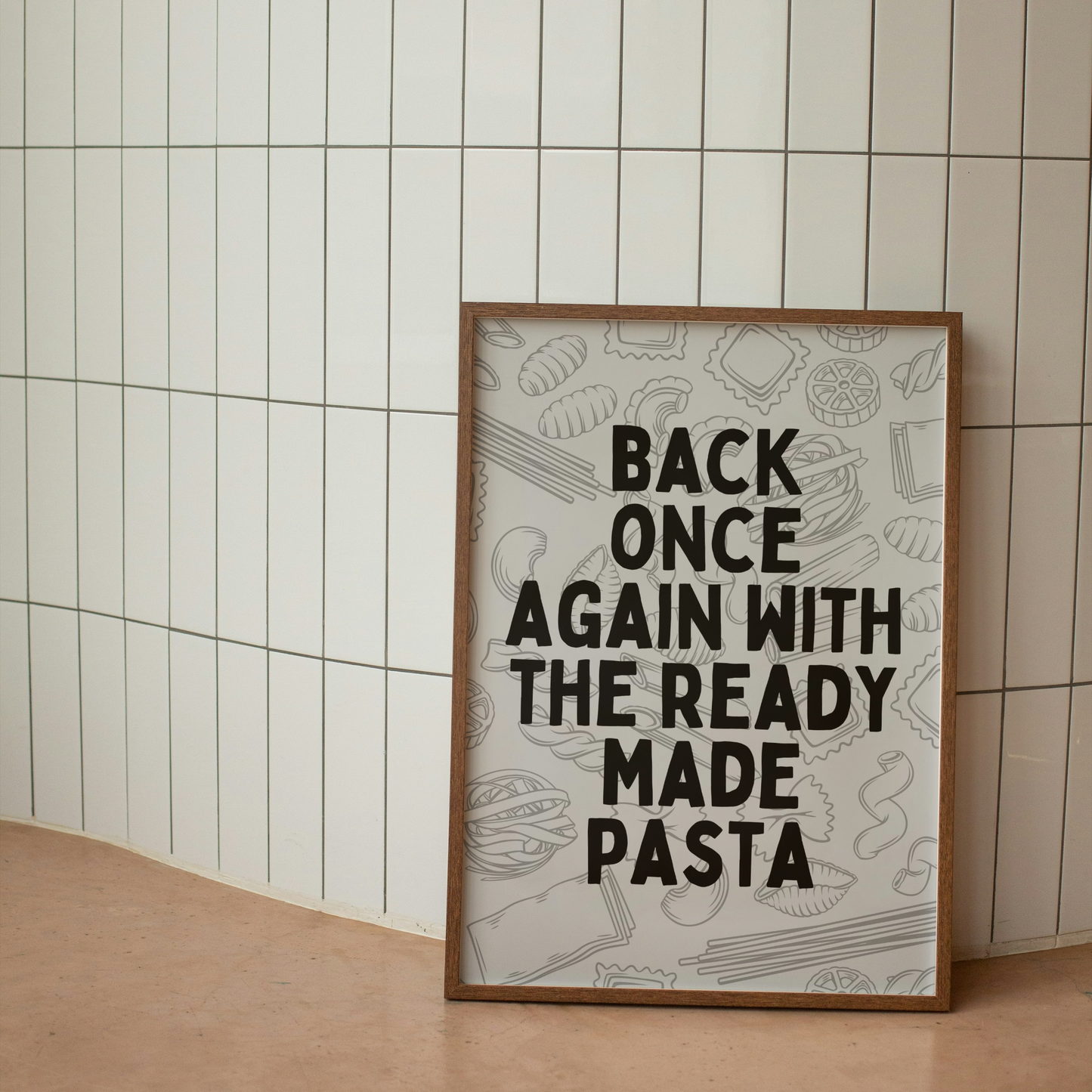 Framed poster with text 'Back once again with the ready made pasta' against a tiled wall.