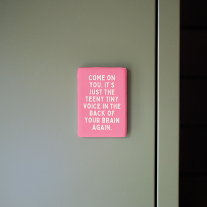 Pink sign with text on a gray wall