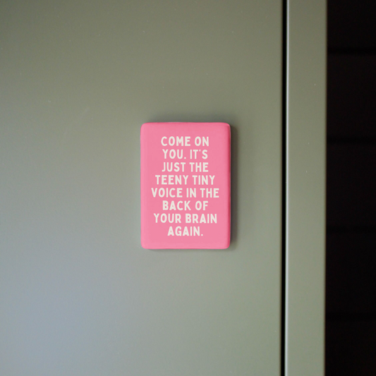 Pink sign with text on a gray wall