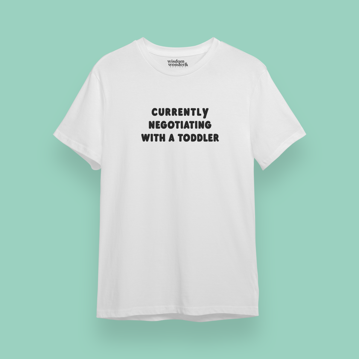 White t-shirt with text 'Currently Negotiating with a Toddler' on a light green background