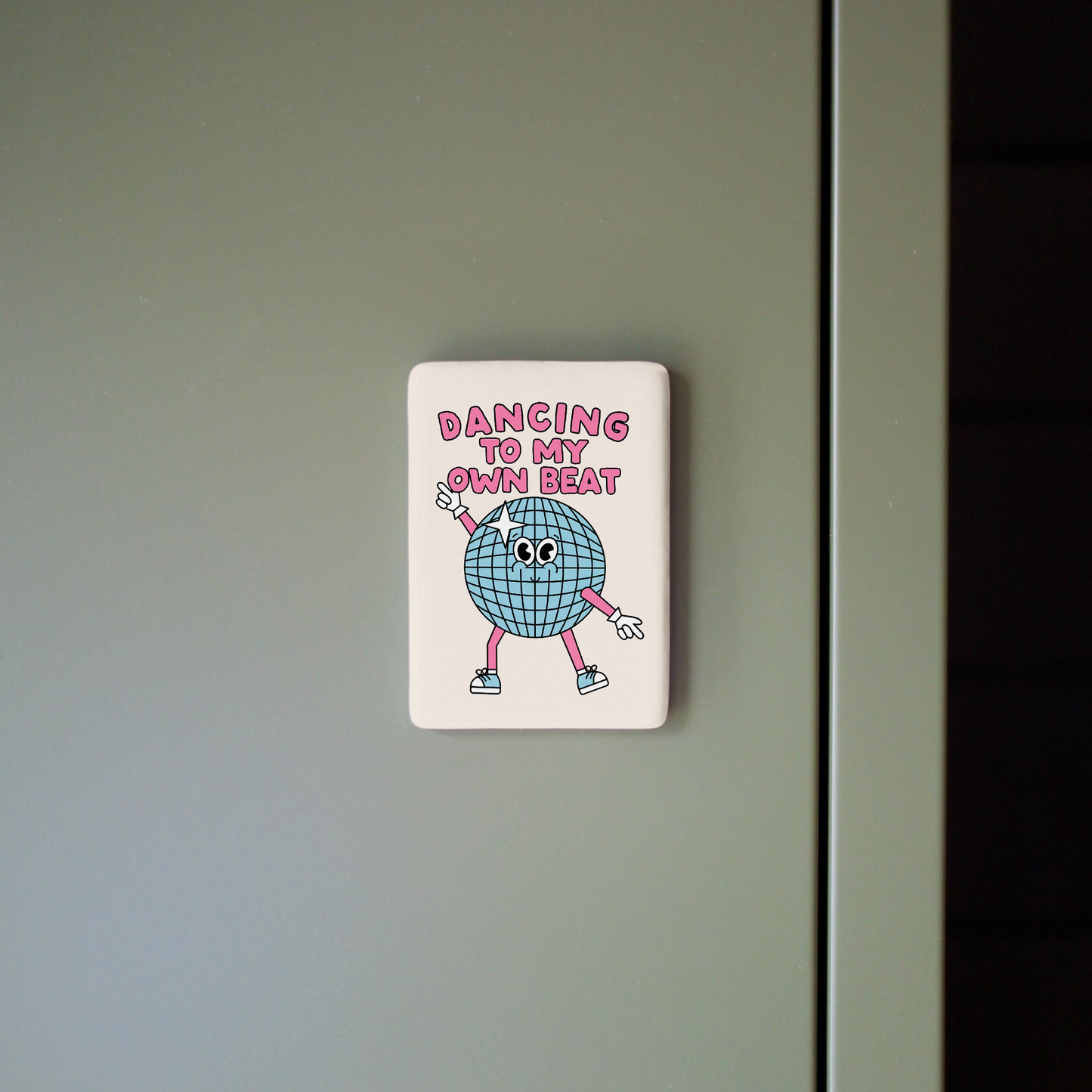 Fridge magnet with cartoon character and text on a gray surface