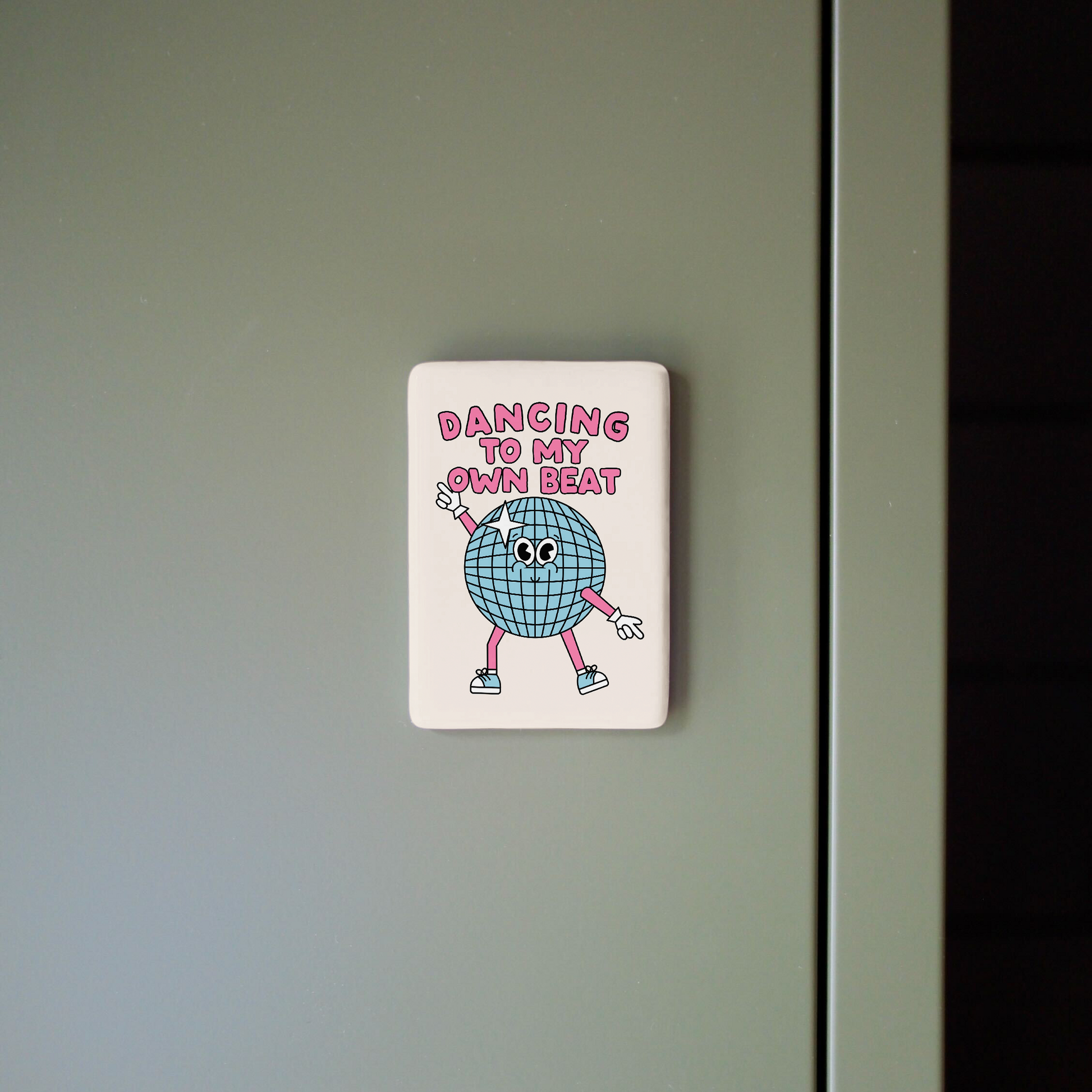 Fridge magnet with cartoon character and text on a gray surface