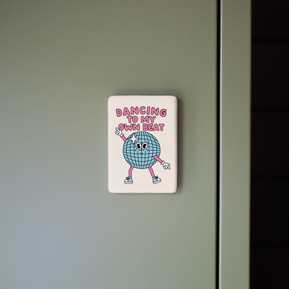 Fridge magnet with cartoon character and text on a gray surface