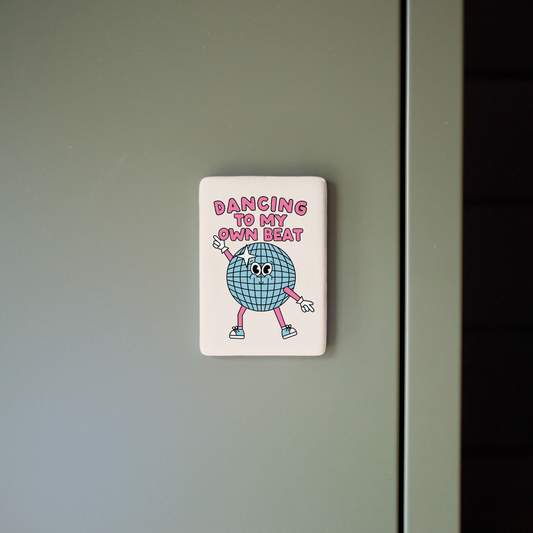 Fridge magnet with cartoon character and text on a gray surface