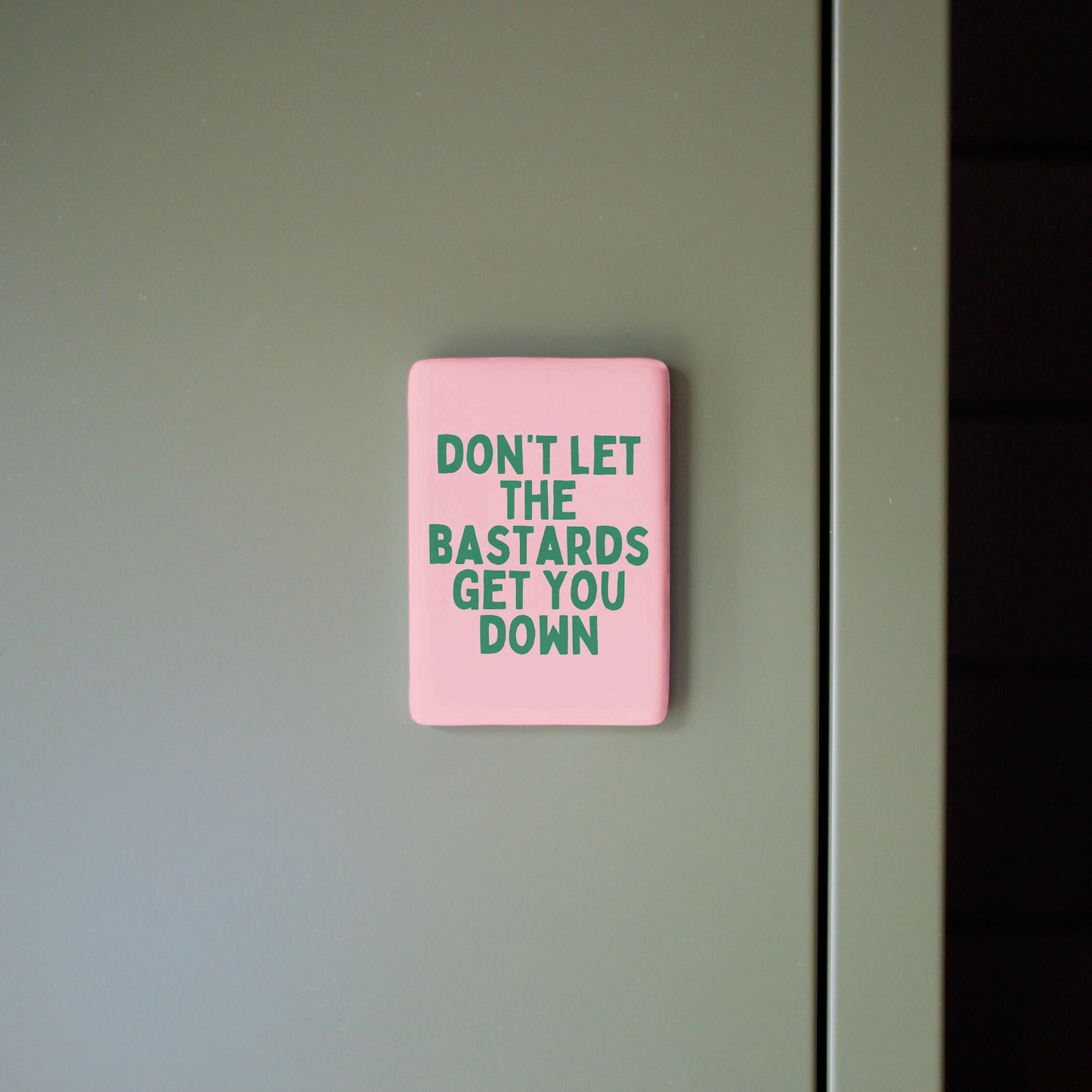 Pink sign with motivational quote on a gray wall