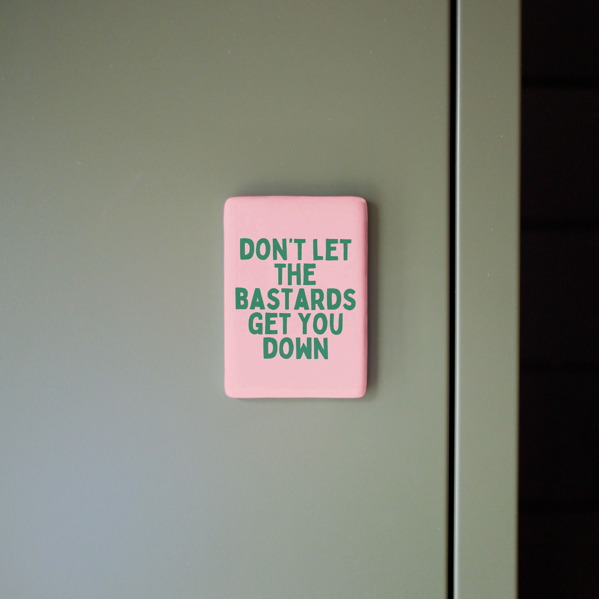 Pink sign with motivational quote on a gray wall