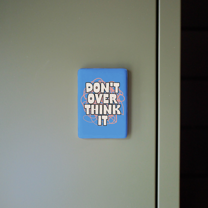 Blue magnet with 'DON'T OVER THINK IT' text on a refrigerator door