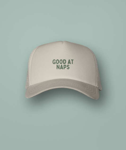 Beige cap with 'GOOD AT NAPS' text on a light green background