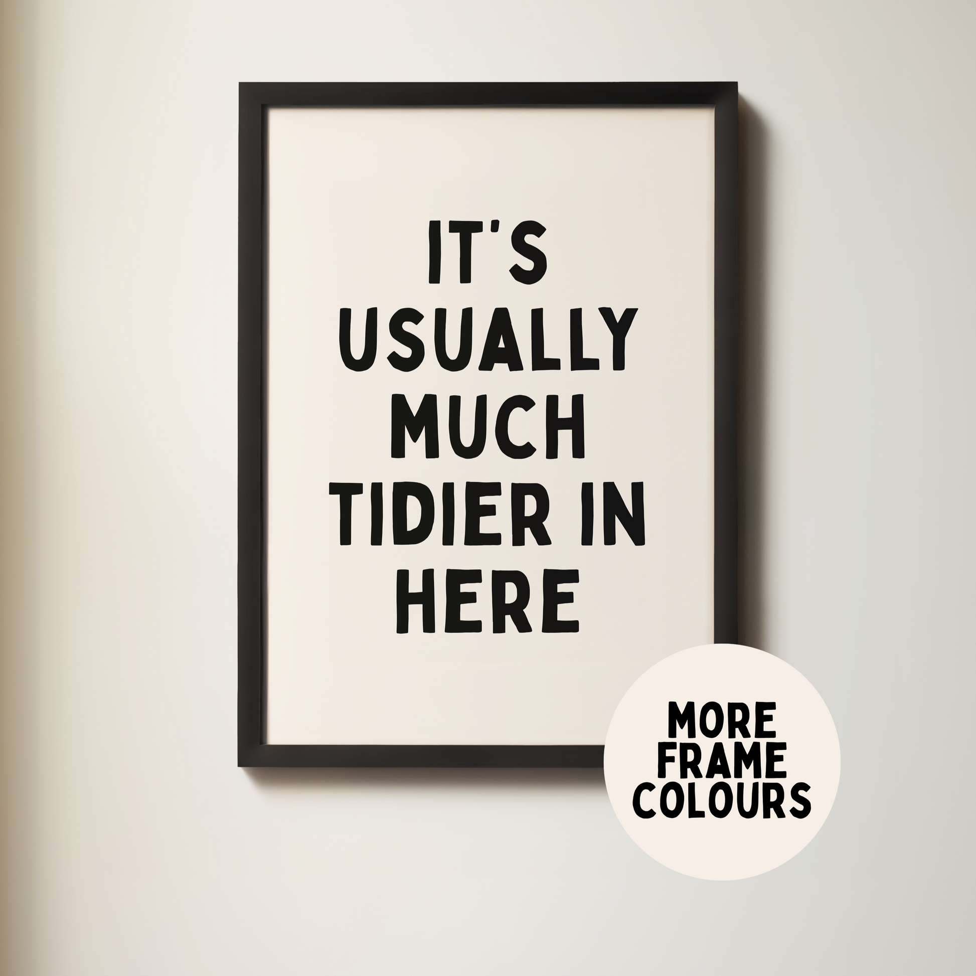 Framed poster with text 'It's usually much tidier in here' on a plain wall.