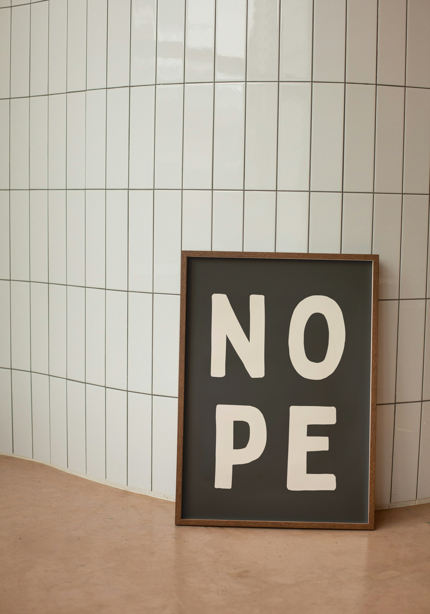 Framed sign with 'NO PE' text against a tiled wall.