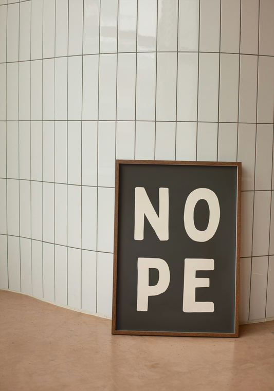 Framed sign with 'NO PE' text against a tiled wall.