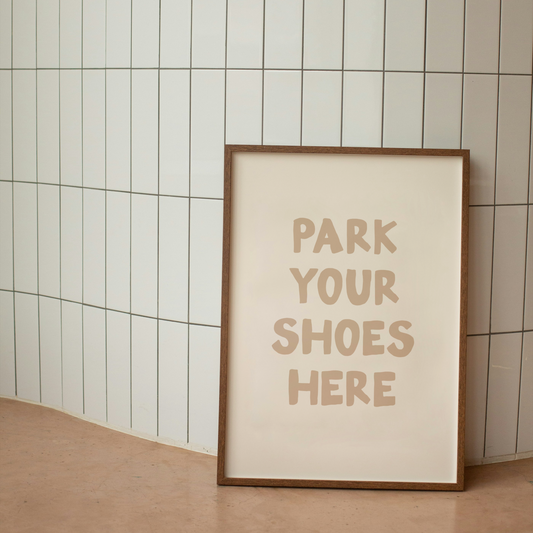 Framed poster with 'Park Your Shoes Here' text against a tiled wall.