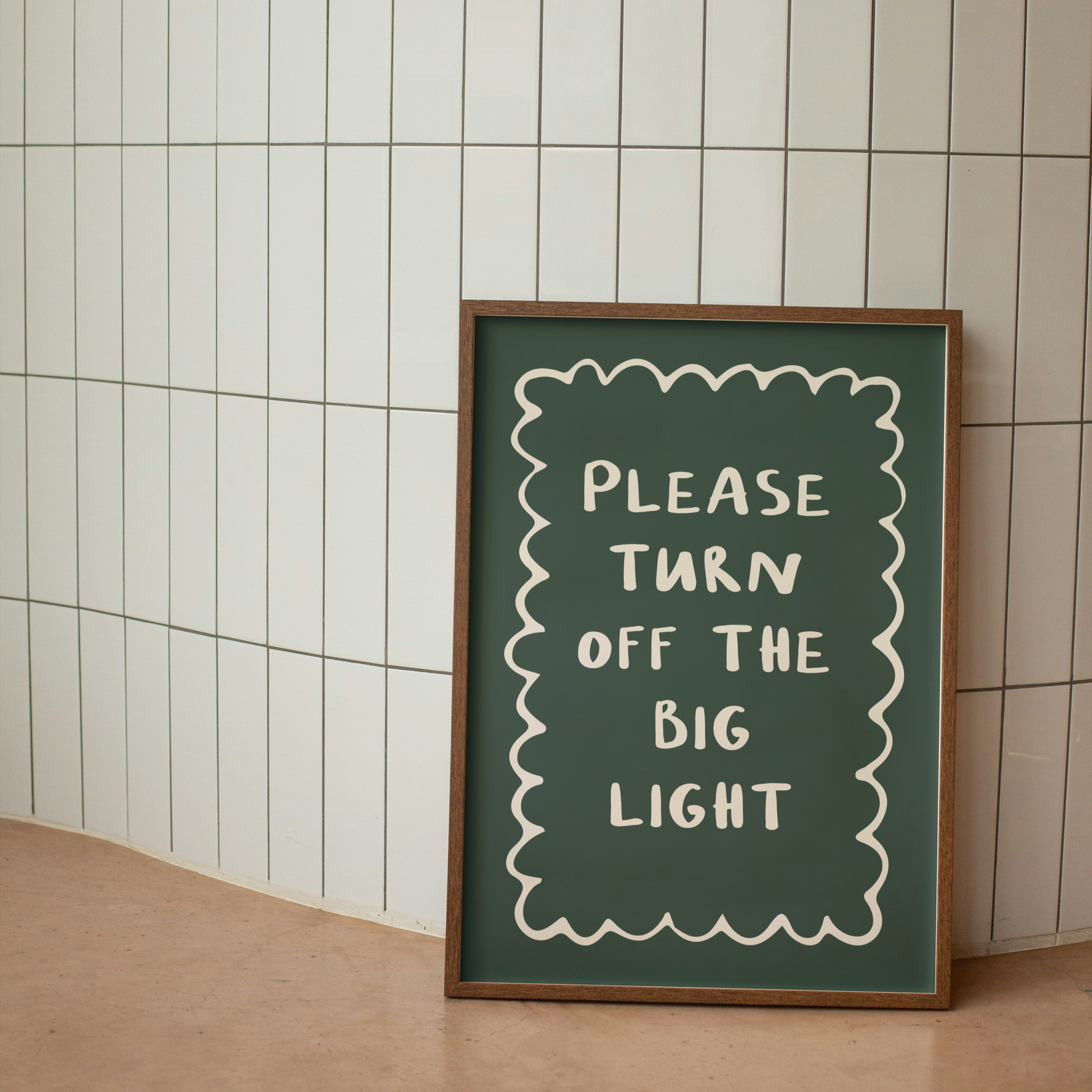 Framed sign with 'Please turn off the big light' text against a tiled wall.