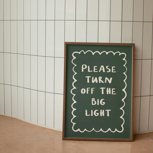 Framed sign with 'Please turn off the big light' text against a tiled wall.