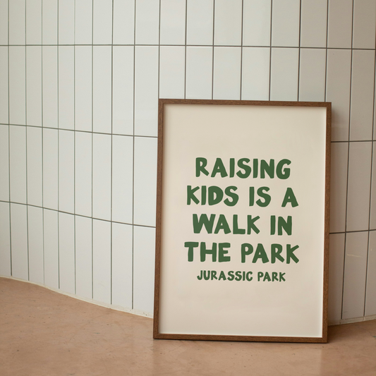 Framed print with text 'Raising kids is a walk in the park' on a tiled wall.