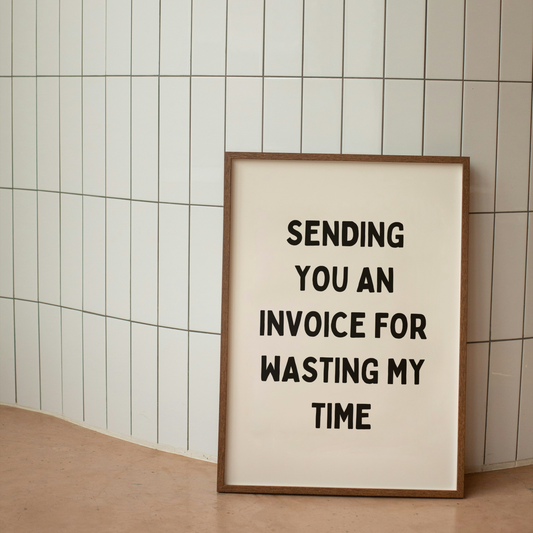 Framed poster with text 'Sending you an invoice for wasting my time' against a tiled wall.