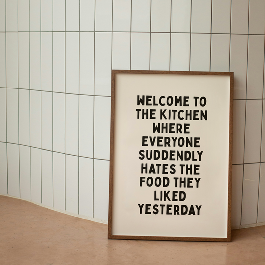 Framed poster with humorous kitchen quote on a tiled wall.