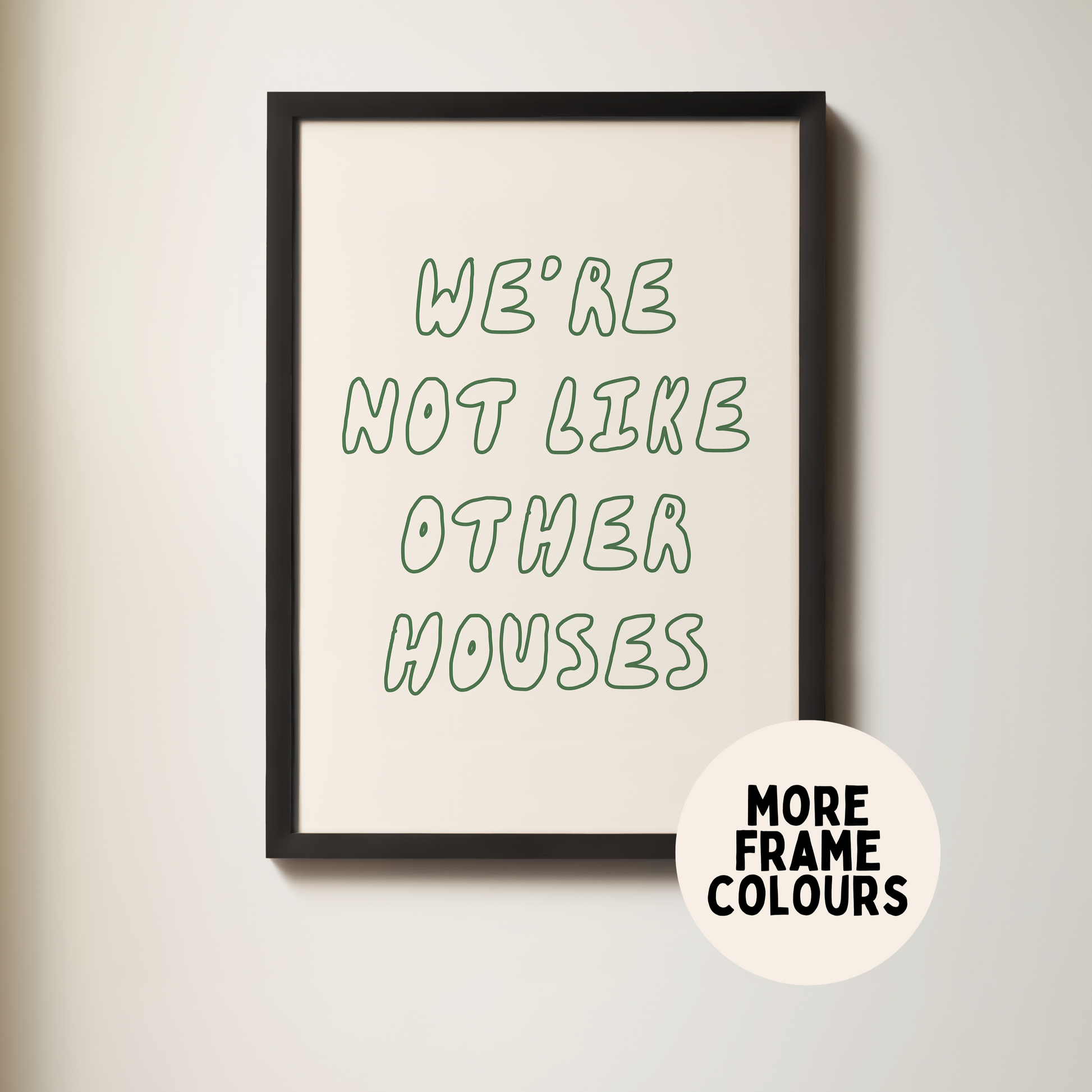 Framed poster with text 'We're not like other houses' on a plain wall.