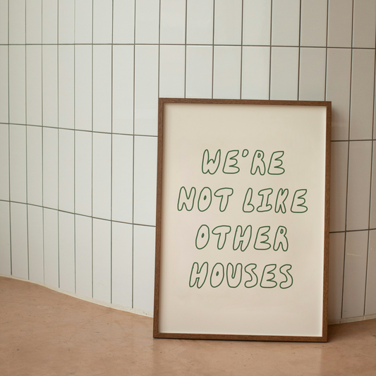 Framed poster with 'We're not like other houses' text against a tiled wall.