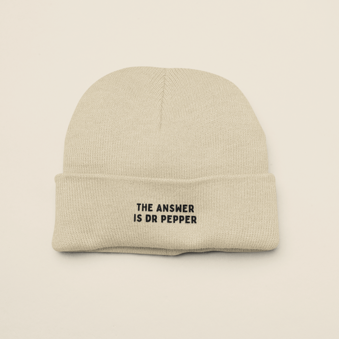 Beige beanie with 'The Answer is Dr Pepper' text on a beige background