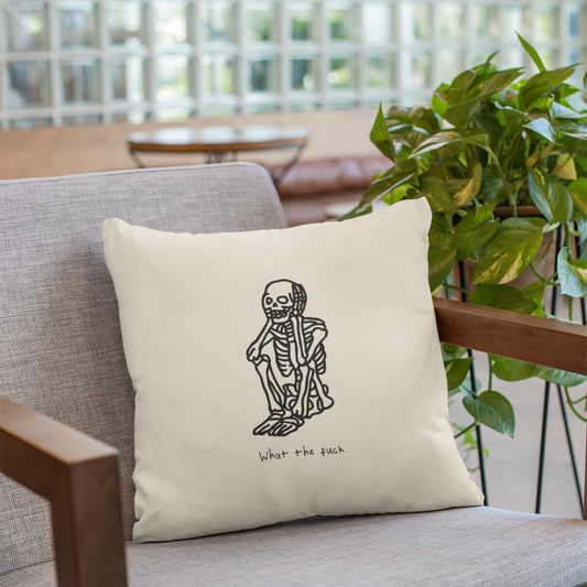 Beige pillow with a skeleton design on a gray sofa with a blurred indoor background